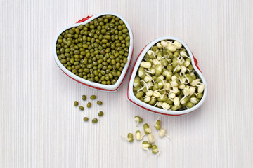 Dry and sprouted mung beans in ceramic bowls of heart shape