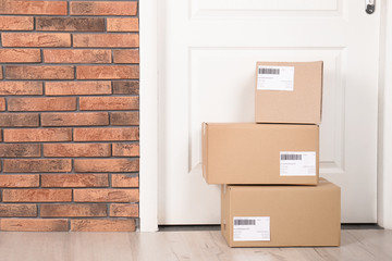 Cardboard parcel boxes on floor near apartment entrance. Mockup for design