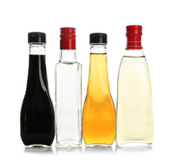 Bottles with different kinds of vinegar on white background