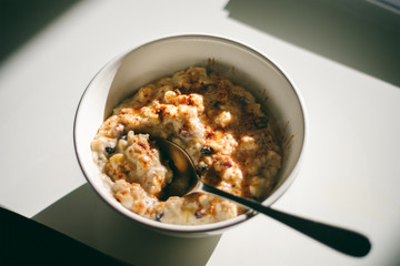 Breakfast porridge in a white bowl with raisins and cinnamon