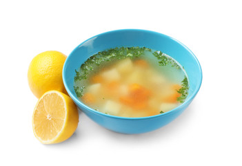 Bowl of fresh homemade soup to cure flu and lemons on white background