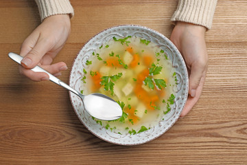 Sick woman eating fresh homemade soup to cure flu at table, top view