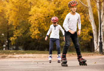 Happy children roller skating in autumn park