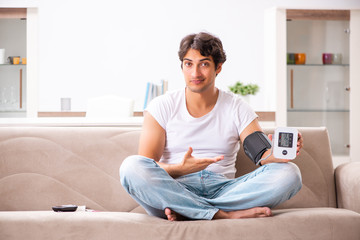 Young man measuring blood pressure at home