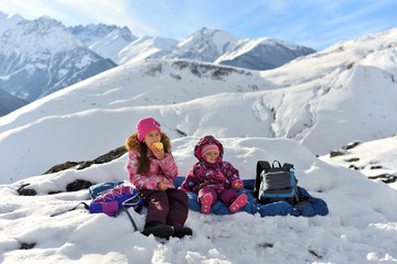 Girls sisters travel in winter in the snowy mountains.