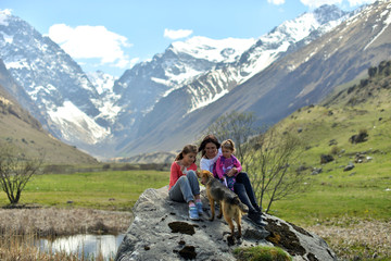 Fototapeta premium Happy family with a dog resting in nature in the mountains