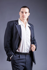 Fototapeta premium Young male confident male posing in gangster style suite. Studio isolated on gray background.