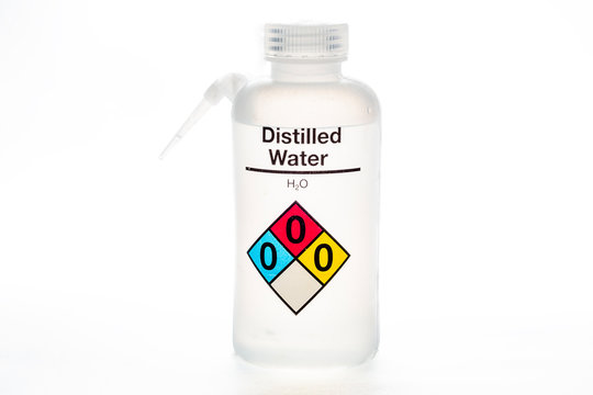 Distilled water bottle used in laboratories with name and safety code.