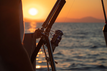 Boat fishing rods over a beautiful sunset seascape horizontal