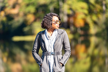 Beautiful young African-American Woman standing in front of lake in autumn