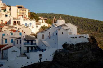 Naklejka premium Skopelos Old Town, Orthodox Church and small greek houses on the hill as seen from the water on a sailing boat or yacht in the harbor