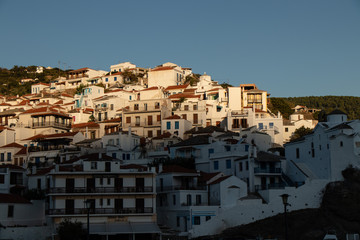 Fototapeta na wymiar Skopelos Old Town and small greek houses on the hill as seen from the water on a sailing boat or yacht in the harbor