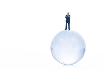 Miniature business man standing on crystal plobe