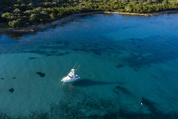 Aerial view of a little fishing boat on a beautiful and transparent sea. Sardinia, Italy..