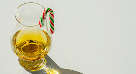 single malt whiskey glass with candy cane, the symbol of Christmas holiday