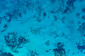 Fototapeta na wymiar Aerial view of a beautiful turquoise and transparent sea that creates a natural pattern.