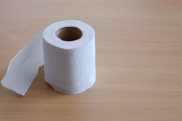 Tissue rolls used for wiping in a white bathroom are placed on a wooden background.