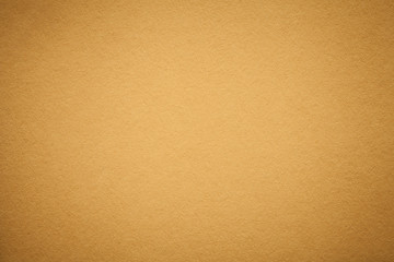 Texture of old golden paper background, closeup. Structure of dense light orange cardboard.