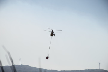 A helicopter from the fire department flying with water in their bucket