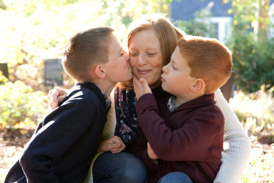 Sons kissing happy mother