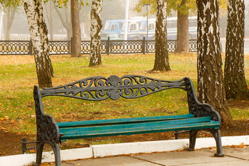 An empty bench is standing in the autumn park.