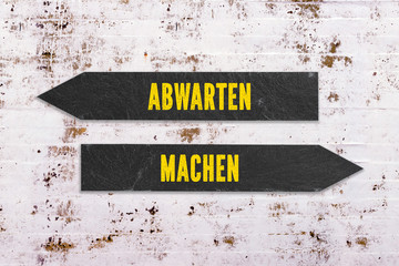 Pfeile mit Text "abwarten" und "machen" als Wegweiser