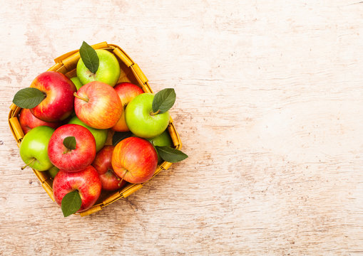 Healthy red and green apples in vintage basket on wooden background.