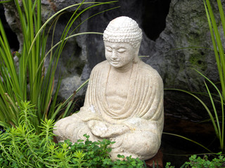 Little white carved Buddha statue in garden