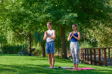 Obraz premium Smiling couple doing yoga exercises outdoors