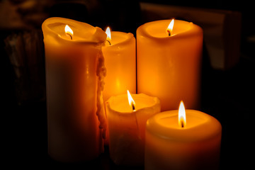 Several burning candles on a dark background.