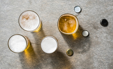 Glasses of beer with reflection on grey concrete textured copy space background