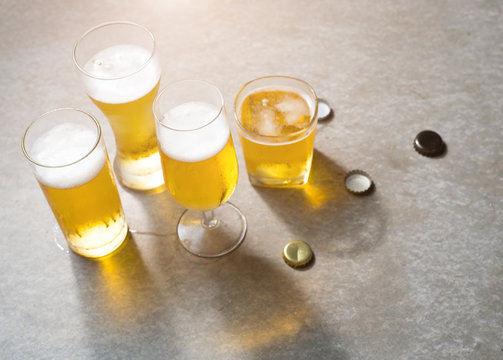 Glasses of beer with reflection on grey concrete textured copy space background