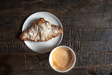 Fresh croissant and cup of cofee  on dark rustic wooden table with copy space. Flat lay. Top view