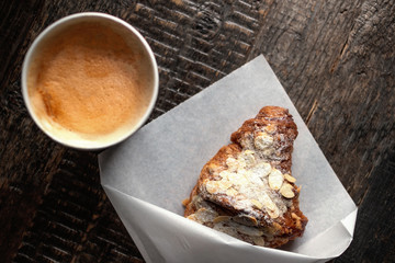 Fresh croissant and cup of cofee  on dark rustic wooden table with copy space. Flat lay. Top view