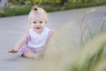 Adorable smiling baby girl sitting in the park pedestrian area