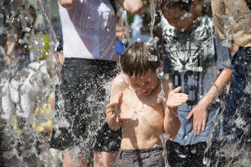 Little boy under the water jets. The child bathes in the fountain. Man in the rain