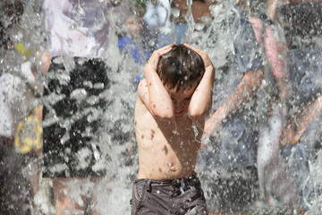 Little boy under the water jets. The child bathes in the fountain. Man in the rain.Bathing in the fountain