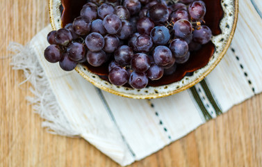 Grapes in a plate on a white towel - top view. Delicious grapes - vitamins and health benefits.