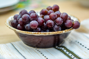 Grapes in a bowl on a table with a white napkin. Autumn abundance - vitamin and healthy food.