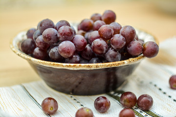 Grapes in a bowl on a table with a white napkin. Autumn abundance - vitamin and healthy food.