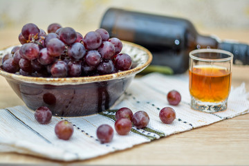 Cognac or Brandy in a glass and fresh grapes, bottle.  vintage wooden background.