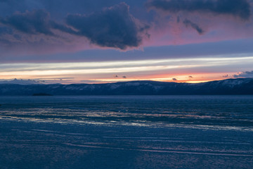 Obraz premium The frozen Lake Baikal. Winter landscape with tranparent ice and snow near the rocks of Olkhon Island in the sunset
