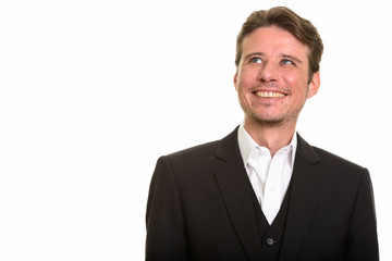 Happy Caucasian businessman thinking while smiling and looking up