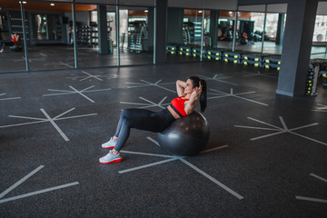 Cheerful female doing abdominal crunches on exercise ball