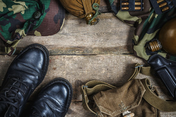 Army military uniform, weapon, holster, pistol, flask, boots on wooden background. Flat lay top...