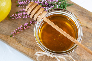 Honey in jar with fresh heather on wooden background
