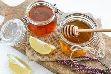 Honey in jar with fresh heather on wooden background