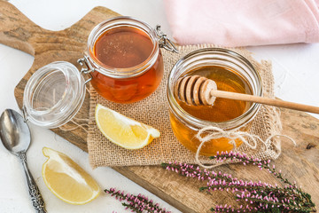 Honey in jar with fresh heather on wooden background