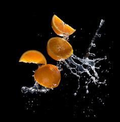 Fresh oranges with water splashes against black background