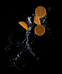 Fototapeta na wymiar Fresh oranges with water splashes against black background